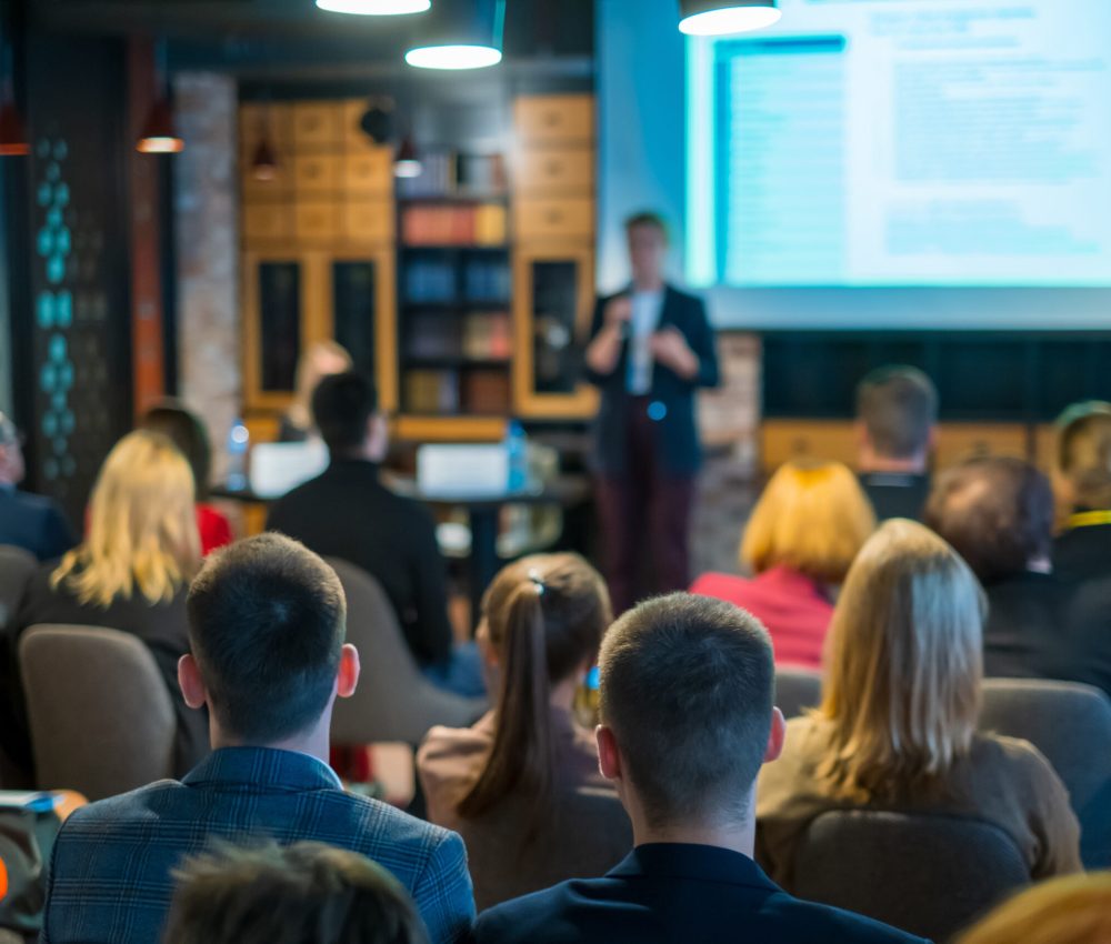 Audience listens lecturer at workshop in conference hall
